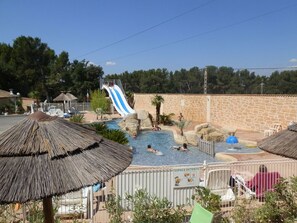 A swimming pool area with a water slide, lounge chairs, and umbrellas. - Camping La Montagne (Sorgues)