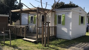 Una casa móvil de una sola planta, pequeña, con un porche y un espacio de estar al aire libre techado.
