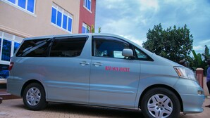 A silver minivan parked in front of a building with a sign reading "RED SOX HOTEL." - Red Sox Hotel (Seeta)