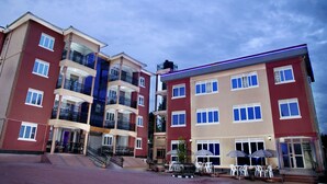 A multi-story hotel with balconies, outdoor seating, and a central staircase. - Red Sox Hotel (Seeta)
