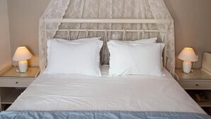 A bedroom with a canopy bed, two bedside lamps, and a blue bedspread.