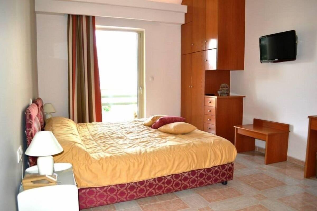 A bedroom with a bed, a desk, a television, and a wardrobe.