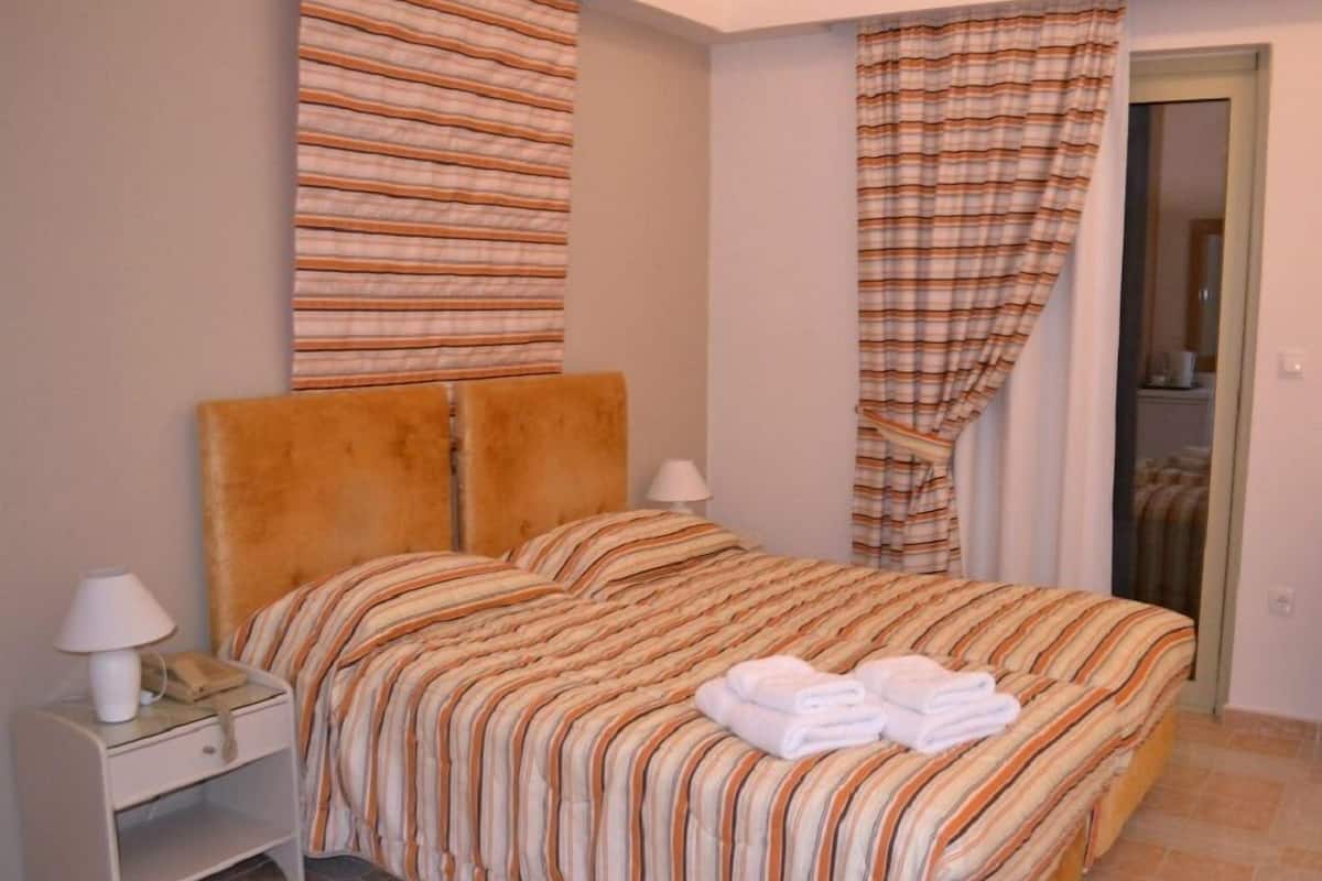 A bedroom with a bed, a nightstand, a lamp, and a door.