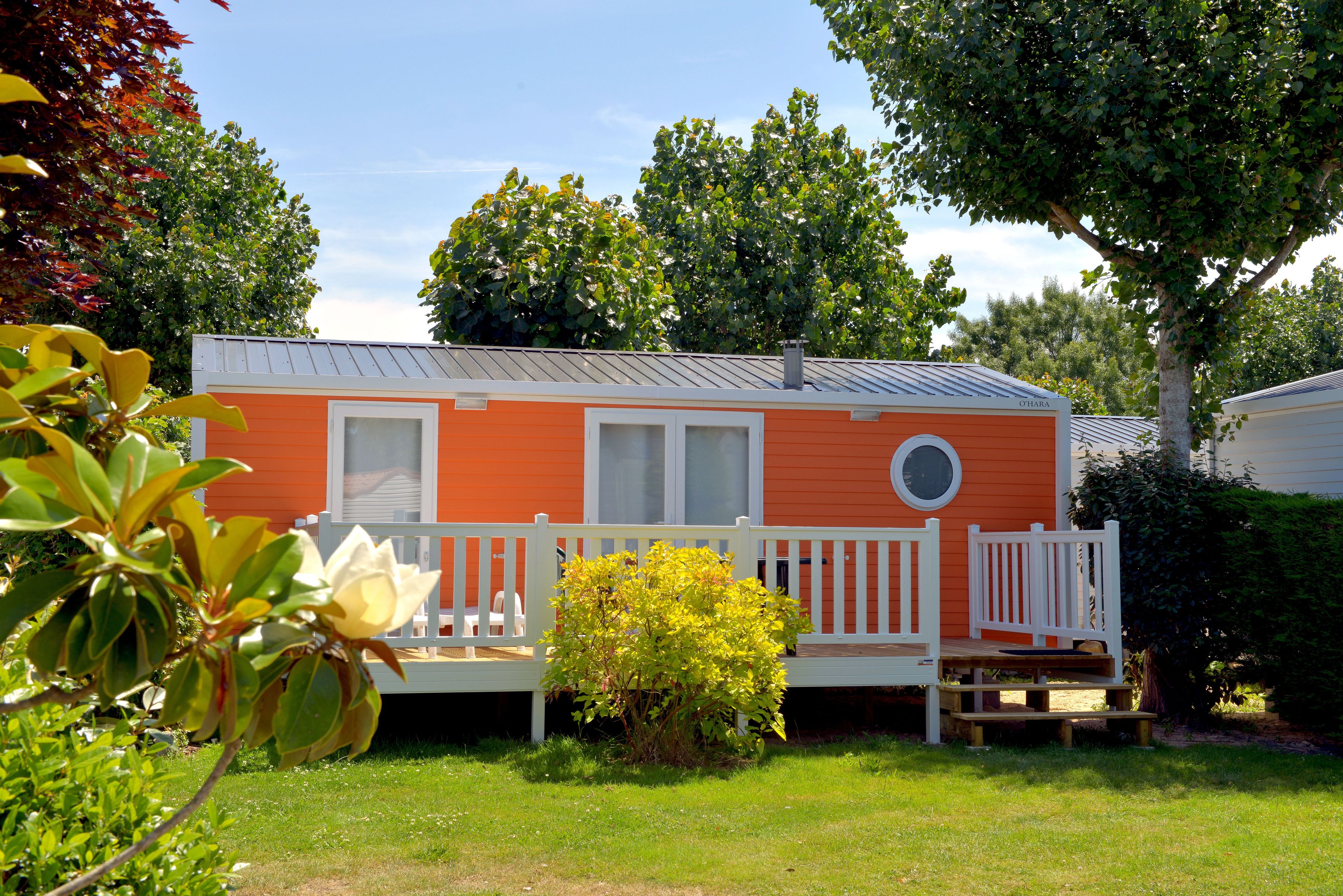 Une maison mobile dotée d’un porche blanc et d’une petite terrasse.