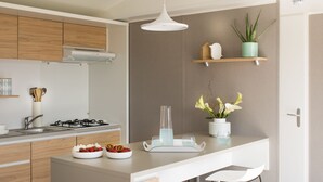 Eine moderne Küche mit einer zentralen Kochinsel, Barhocker, einer Pendelleuchte und einem Blumentopf.