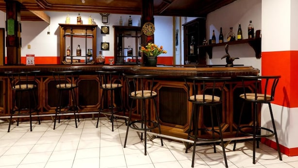 A bar area with wooden bar stools and a tiled floor. - RedDoorz Plus @ Samratulangi Manado (Manado)