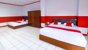 A hotel room with two beds, a wardrobe, and a nightstand. - RedDoorz Plus @ Samratulangi Manado (Manado)