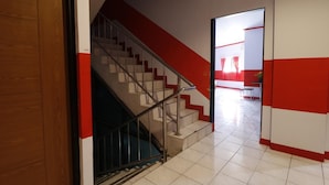 A staircase with a metal handrail leading to a room with red and white walls. - RedDoorz Plus @ Samratulangi Manado (Manado)