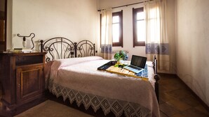 A bedroom with a bed, a desk with a laptop, a lamp, and a window with curtains. - Sas Abbilas (Bonorva)