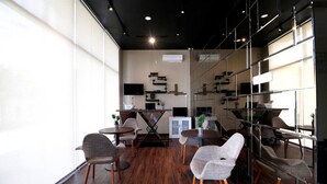 Un interior modern amb sòl de fusta, mobles contemporanis i grans finestres que deixen entrar llum natural.