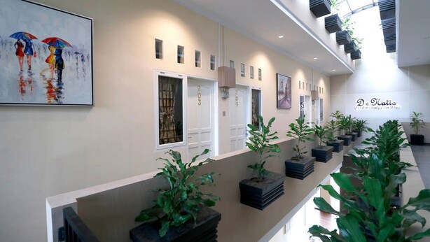 Un passadís d'hotel modern amb una llarga recepció, plantes en testos i obres d'art a les parets.