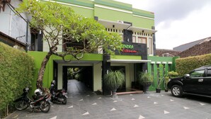 A building with a green facade, a sign reading "HENDRA Extension," and a black car parked in front.