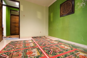 A room with green walls, a wooden door, and patterned rugs on the floor. - RedDoorz Plus @ Taman Siswa 2 (Yogyakarta)