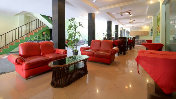 A spacious lobby with red sofas, a glass coffee table, and a staircase leading to an upper level.