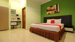 A hotel room with a bed, a nightstand, a dresser, and a mirror.