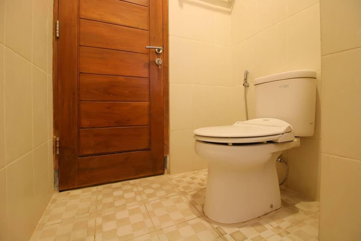 Une salle de bain avec une porte en bois, des toilettes blanches et des carreaux de sol à motifs.