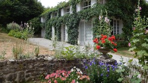 Een gebouw met een stenen muur en een tuin vol verschillende bloemen en planten.