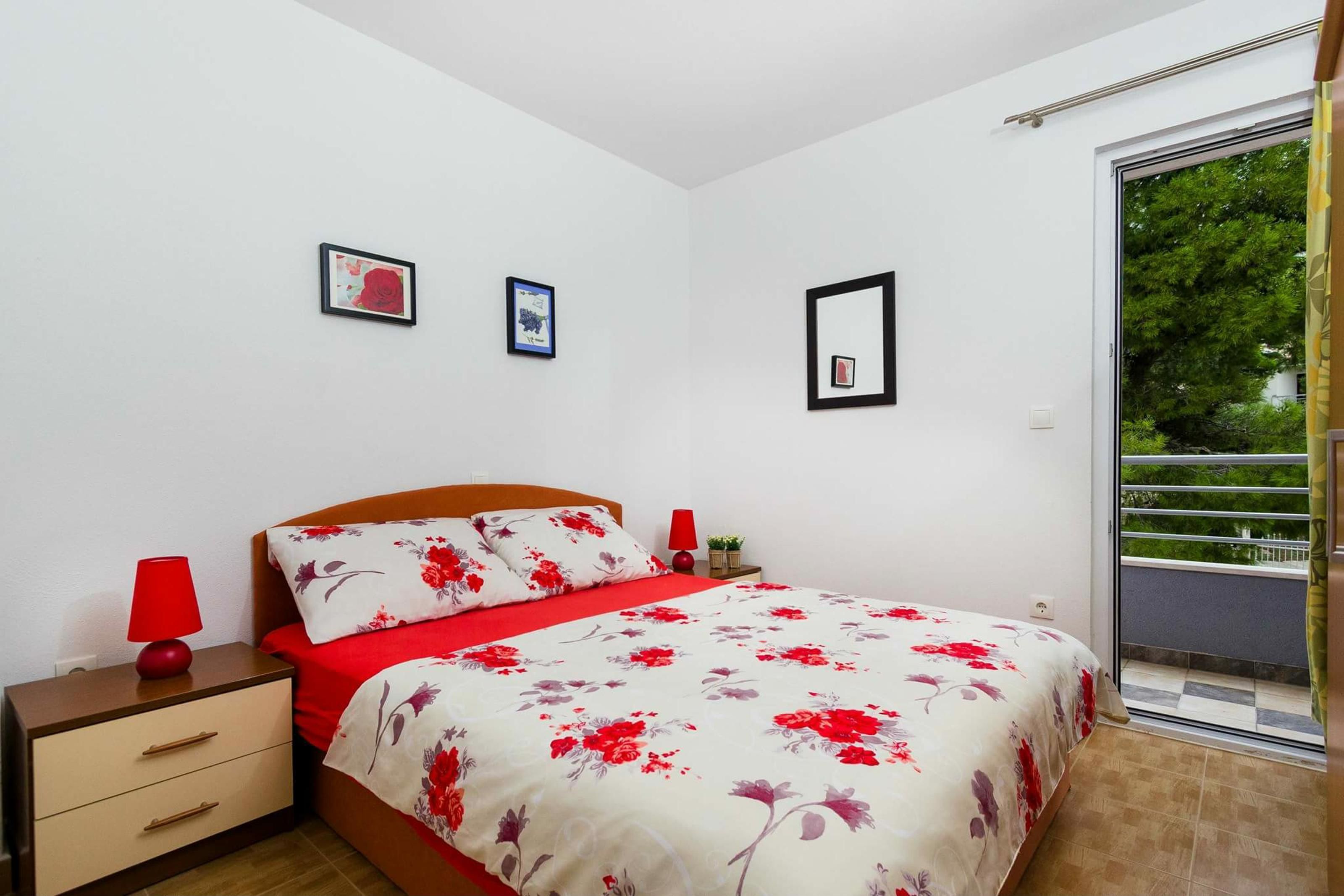 Un dormitorio con cama, mesitas de noche y puerta corrediza de vidrio a un balcón.