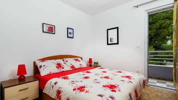 Un dormitorio con cama, mesitas de noche y puerta corrediza de vidrio a un balcón.