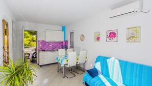 A compact living space with a dining area, kitchenette, and a sofa. - Apartments Andrijanic (Baska Voda)