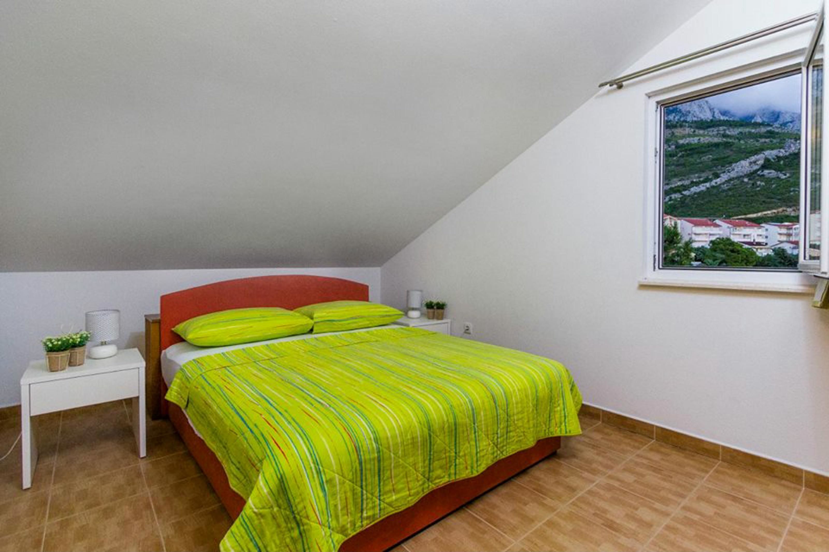 Une chambre à coucher comprenant un lit, une table de chevet, une fenêtre donnant sur un paysage montagneux et une tête de lit rouge.
