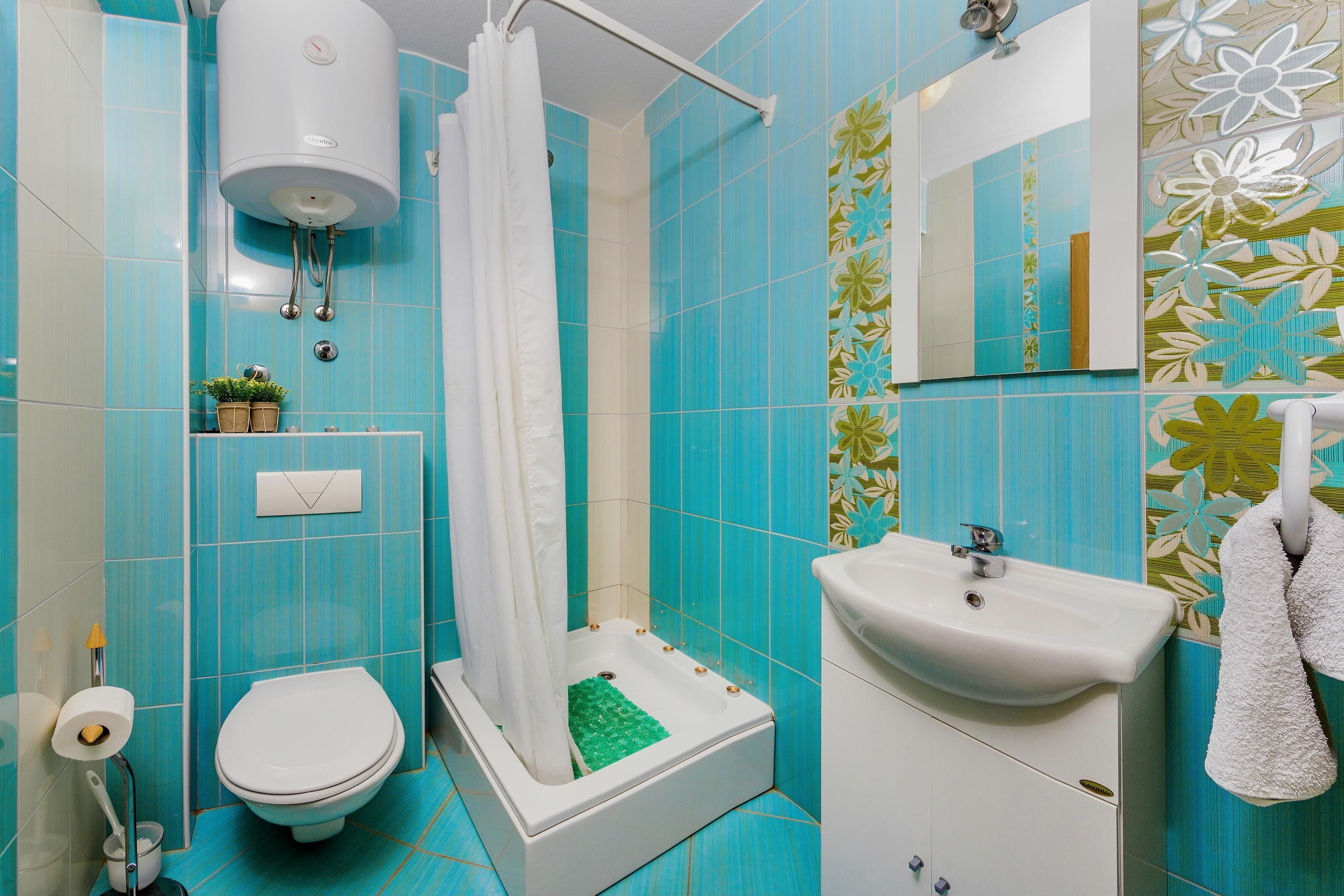 Une salle de bain équipée d’une douche, de toilettes, d’un lavabo et d’un miroir.
