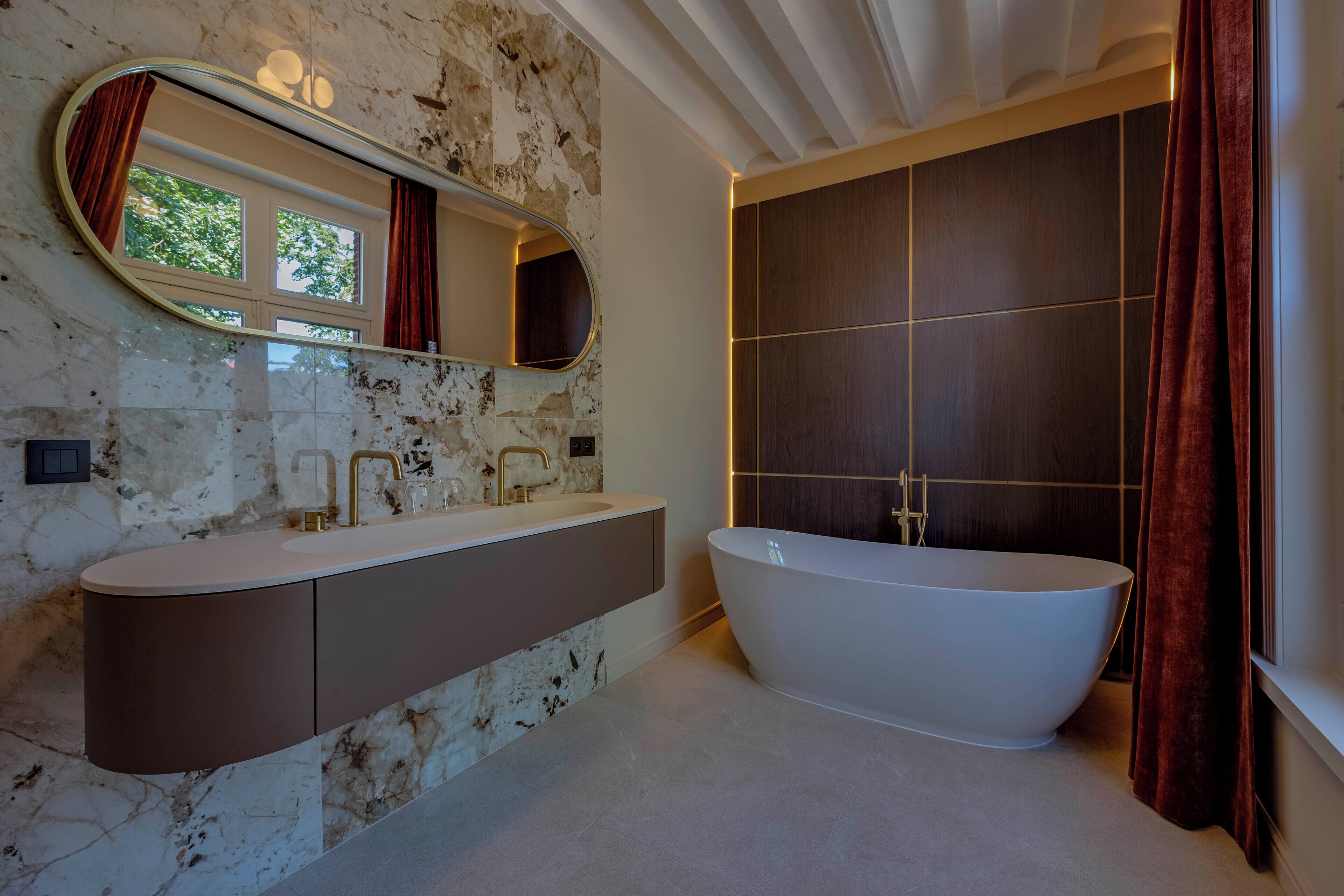 A bathroom with a freestanding bathtub, a large mirror, and a vanity with a marble backsplash.