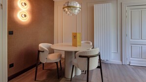 A dining area with a round table, four chairs, a chandelier, and a door with a white panel. - Roosendaelhof (Geel)
