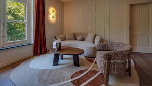 A living room with a sofa, a patterned armchair, a coffee table, and a rug. - Roosendaelhof (Geel)