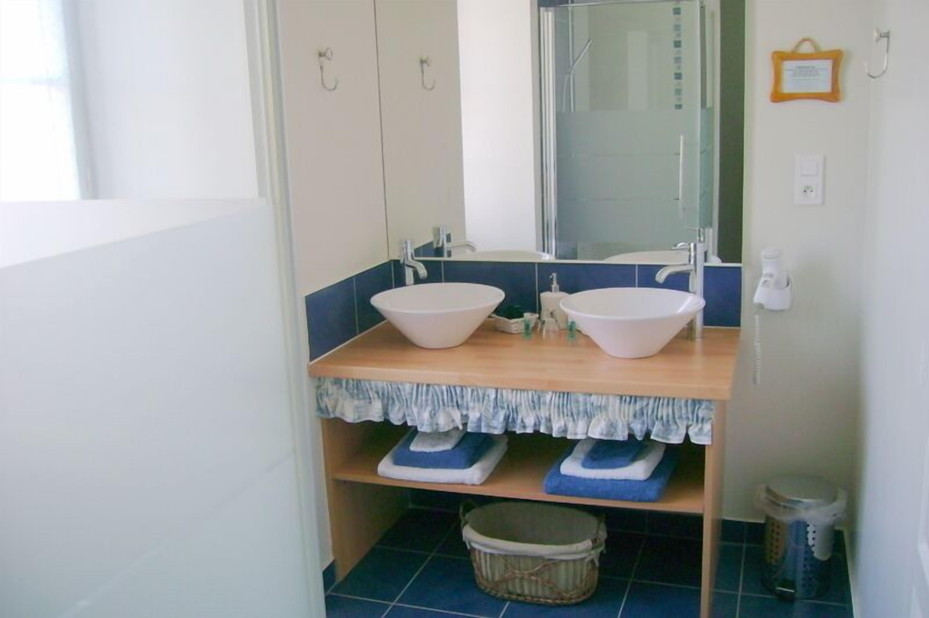 A bathroom with two sinks, a mirror, and a shower.