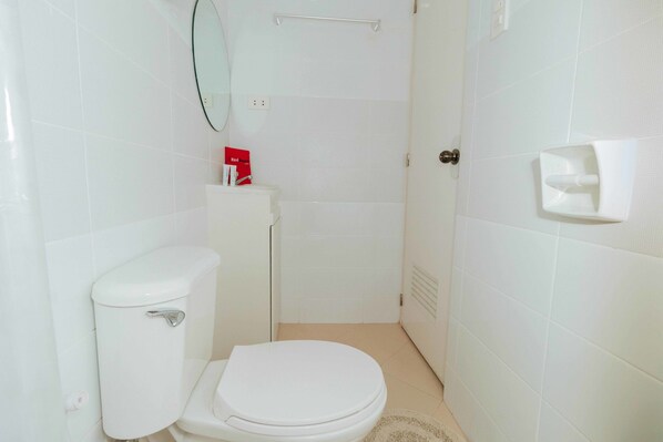 A small, white bathroom with a toilet, a mirror, and a hand dryer. - RedDoorz Plus @ Ruby Las Pinas Weekly Stay (Las Pinas)