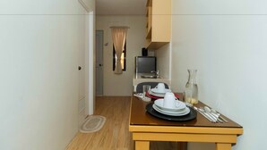 Une cuisine compacte comprenant une table à manger pour deux personnes, un réfrigérateur et un petit plan de travail.