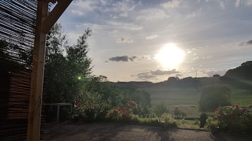 En uteplats med utsikt över en solnedgång över ett kuperat landskap.