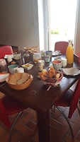 A breakfast table with bread, pastries, and beverages.