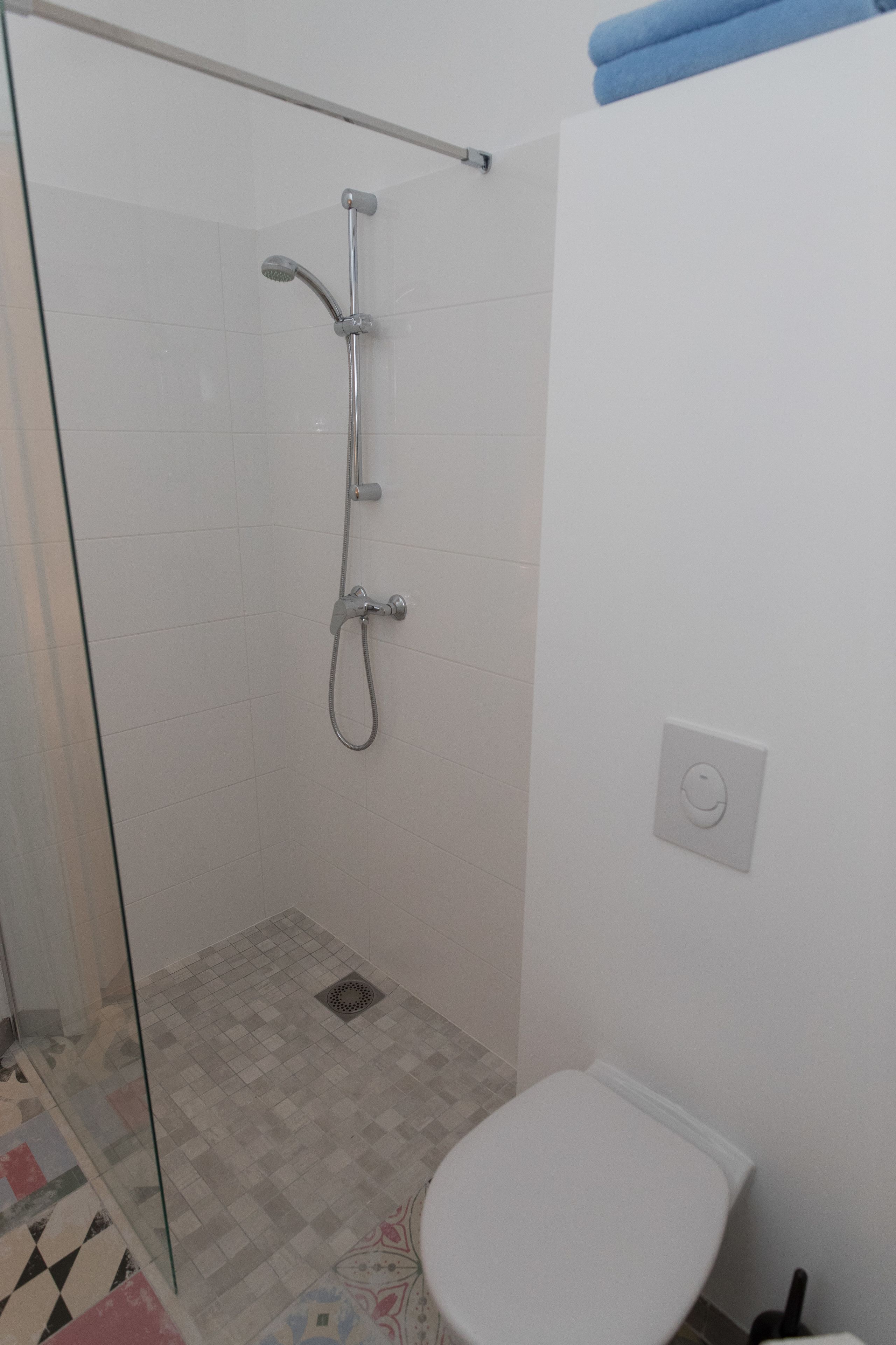 Une salle de bain avec une douche à parois de verre, des toilettes et un sol carrelé.
