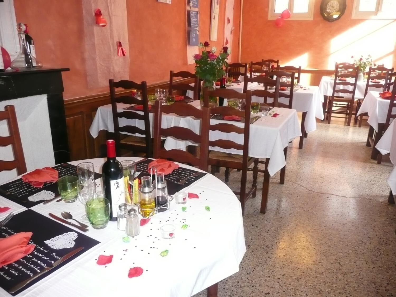 A restaurant with round tables, white tablecloths, and wooden chairs.