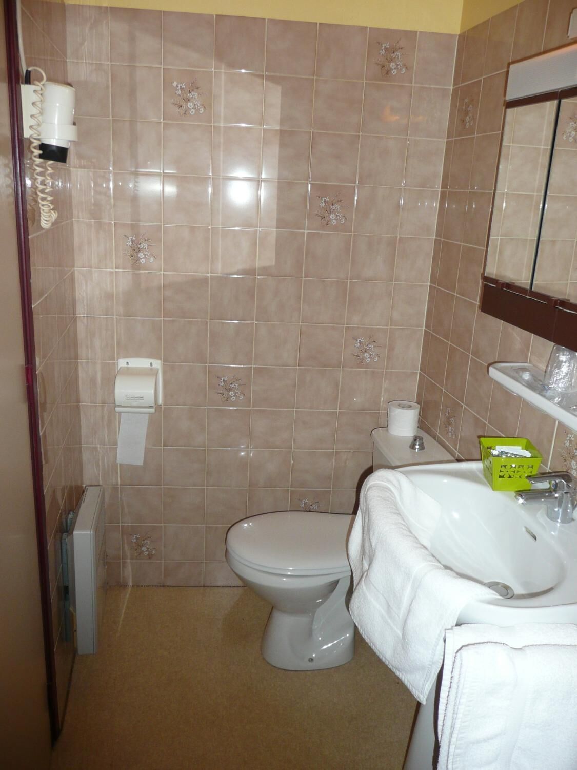 A small bathroom with a toilet, sink, and mirror.