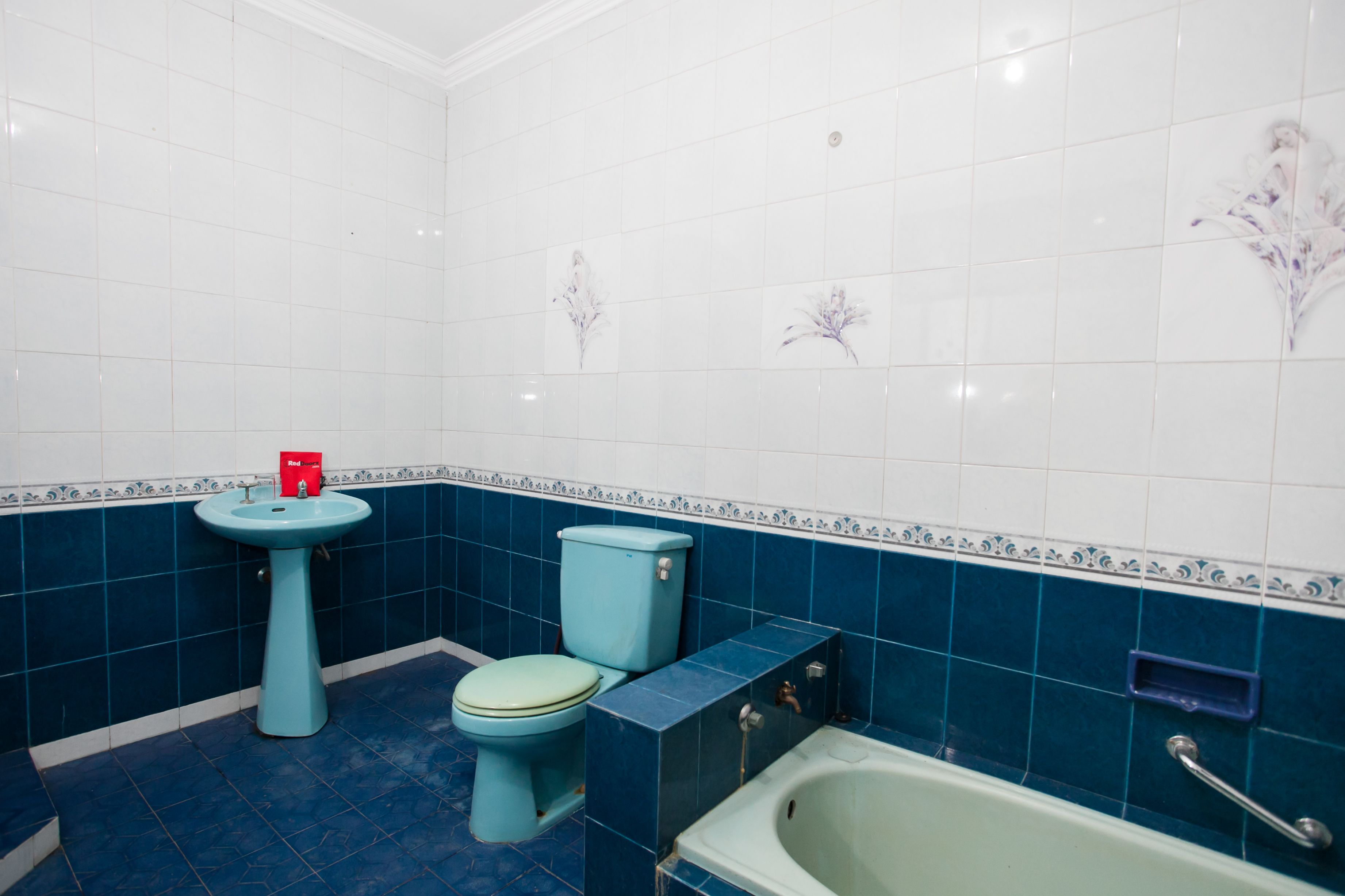 A bathroom with a sink, toilet, and bathtub, featuring blue and white tiles.