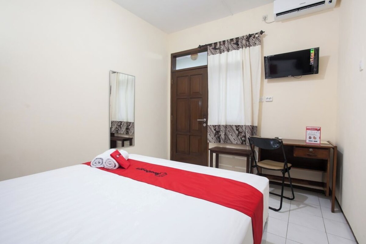 Une chambre d’hôtel avec un lit, un bureau, une chaise, une télévision et une porte.