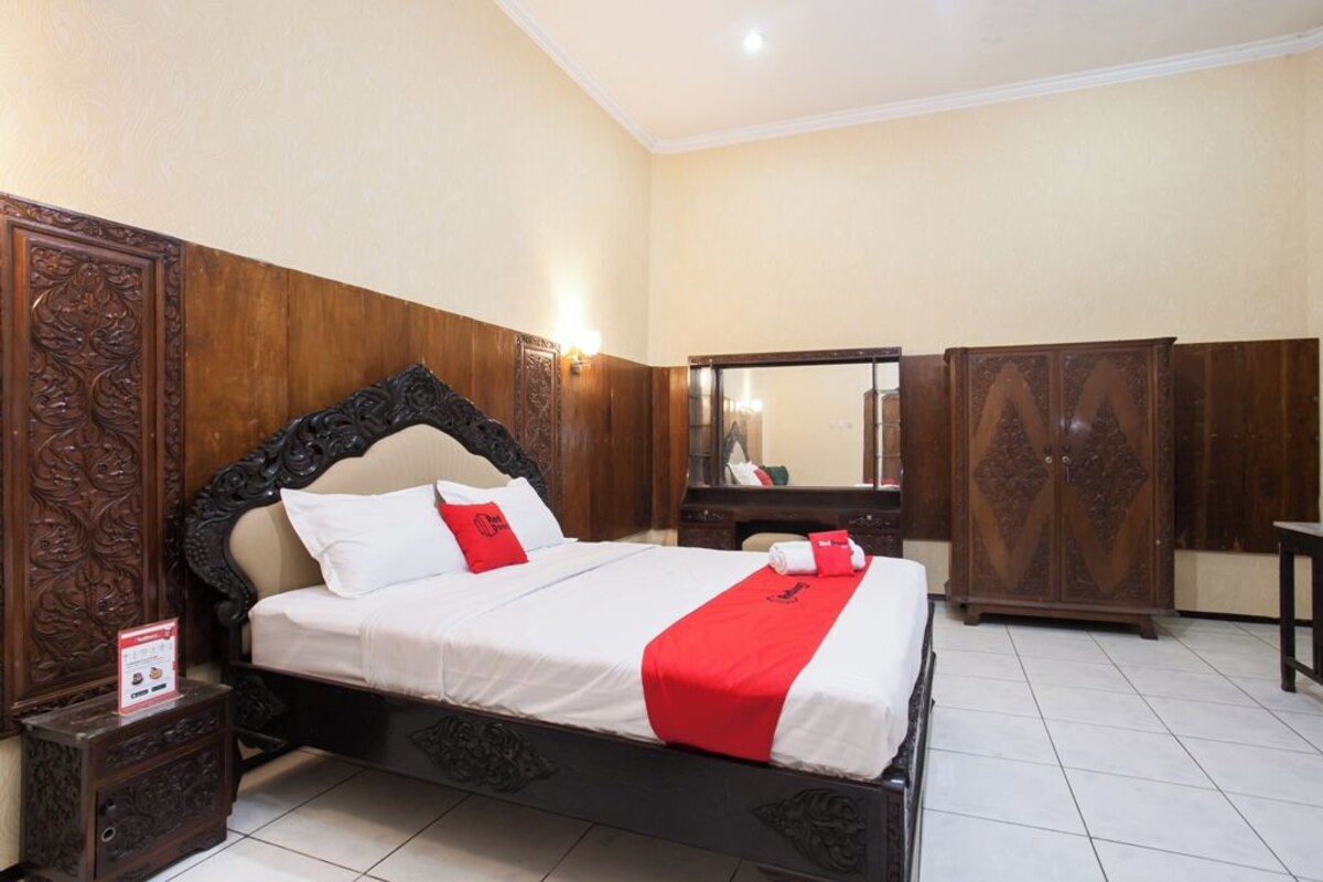 Une chambre d’hôtel avec un grand lit, une tête de lit en bois et une armoire.