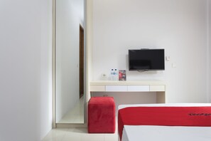 A hotel room with a bed, a desk, a television, and a red chair.