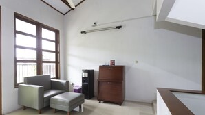 A room with a sofa, ottoman, and a refrigerator. - RedDoorz Plus near Cilandak Town Square 2 (Jakarta)