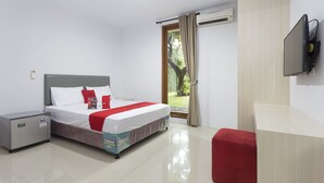 A hotel room with a bed, a small desk, a TV, and a sliding glass door to the outside. - RedDoorz Plus near Cilandak Town Square 2 (Jakarta)