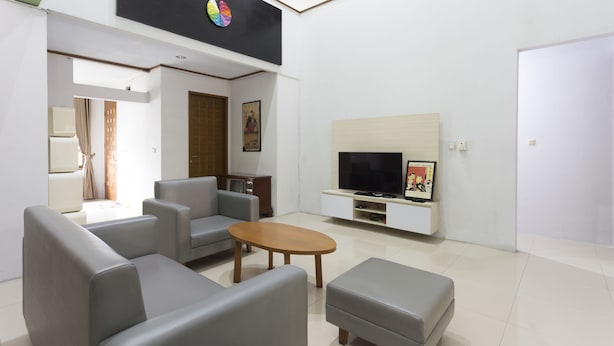 A modern living room with grey sofas, a wooden coffee table, and a TV on a white cabinet. - RedDoorz Plus near Cilandak Town Square 2 (Jakarta)