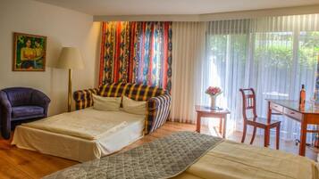 A hotel room with a bed, a chair, a desk, and a window with curtains.
