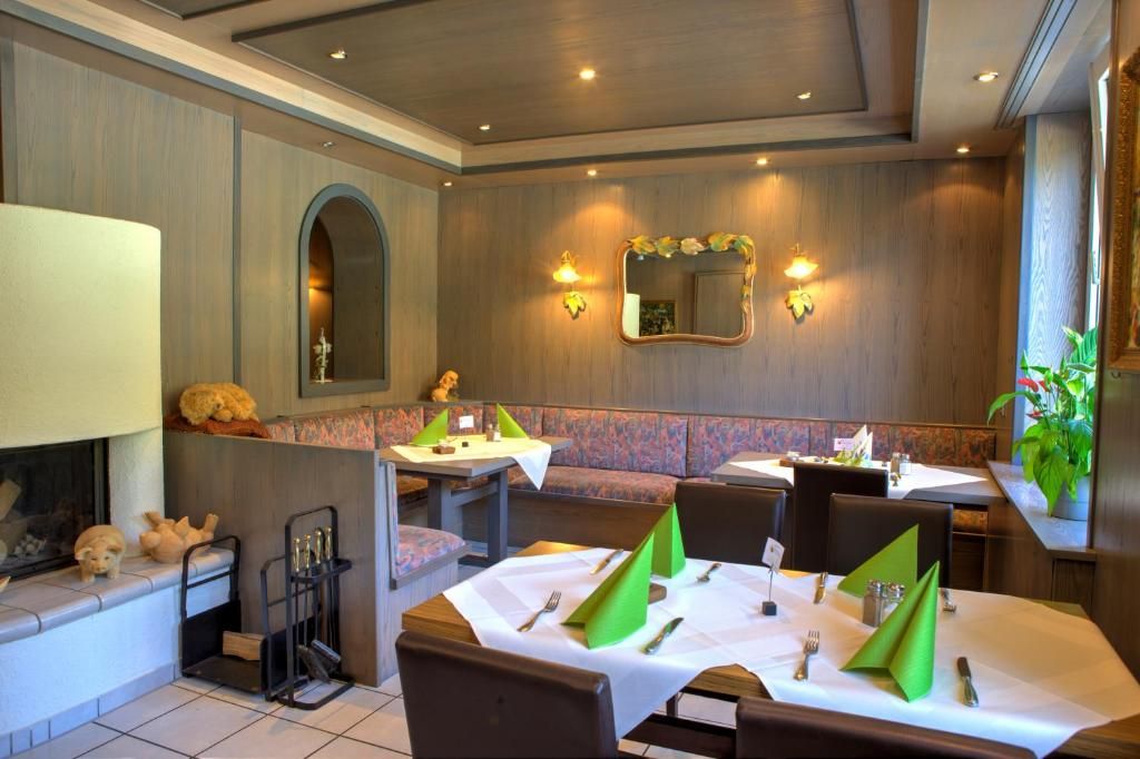 Un ristorante con banquette e tavoli, ognuno apparecchiato con posate e tovaglioli, e uno specchio a parete.
