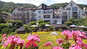 Un hôtel composé de plusieurs bâtiments, doté d’espaces de détente en plein air et d’un jardin agrémenté de fleurs roses.