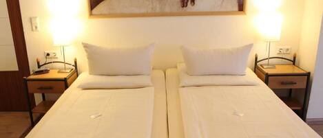 Cama doble con dos mesitas de noche, cada una con una lámpara, en una habitación con un cuadro sobre la cama.