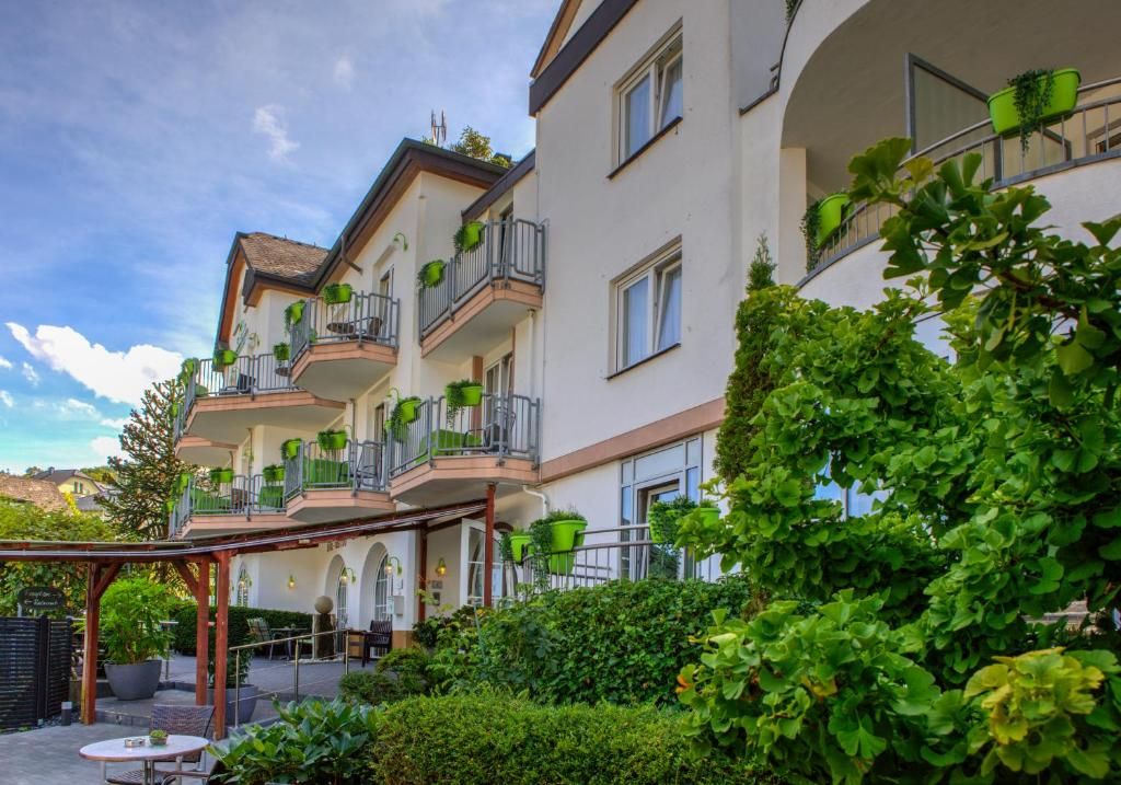 A multi-story building with balconies, outdoor seating, and greenery.