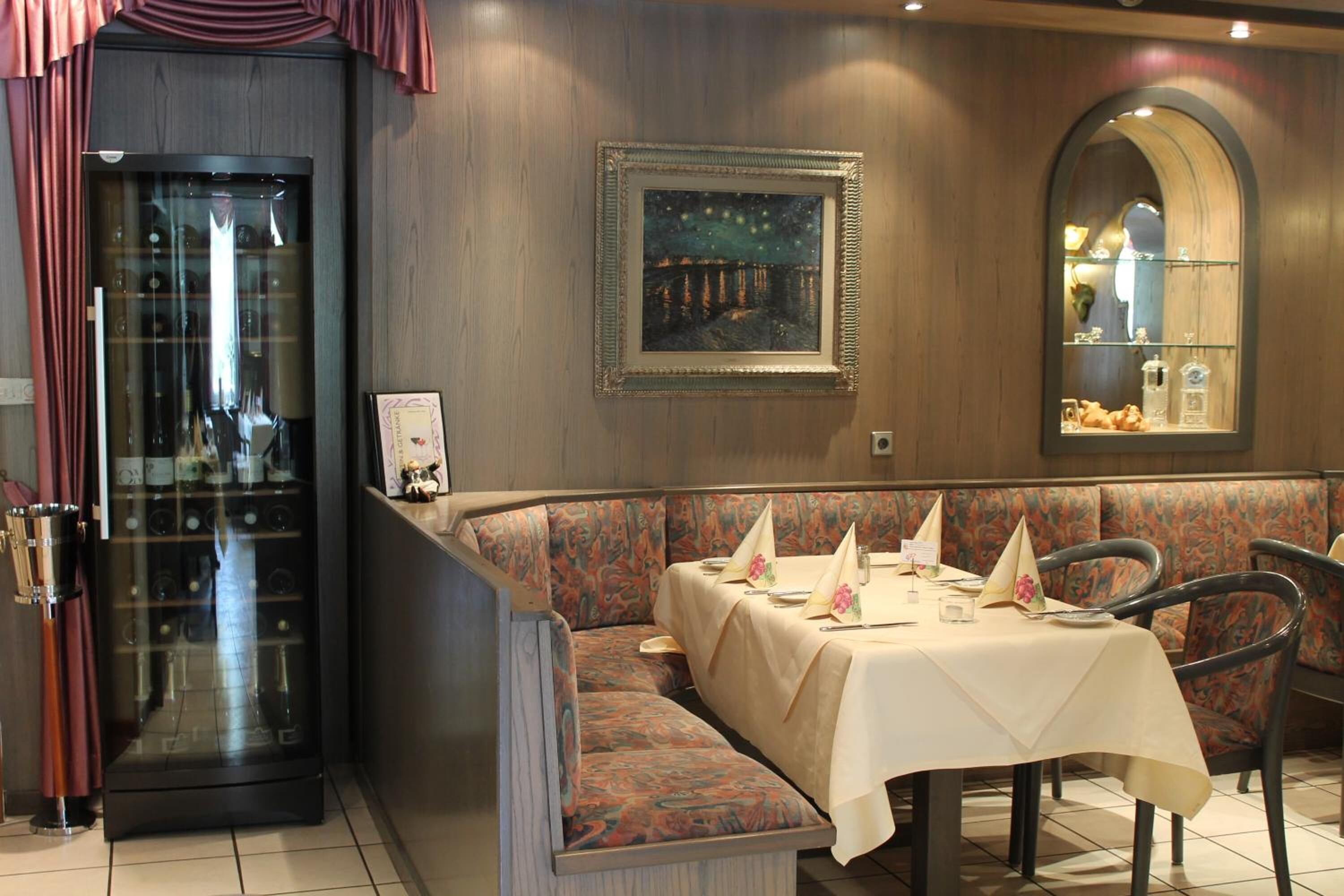 Un restaurante con zona de asientos tipo cabina, una mesa preparada para una comida y un cuadro en la pared.